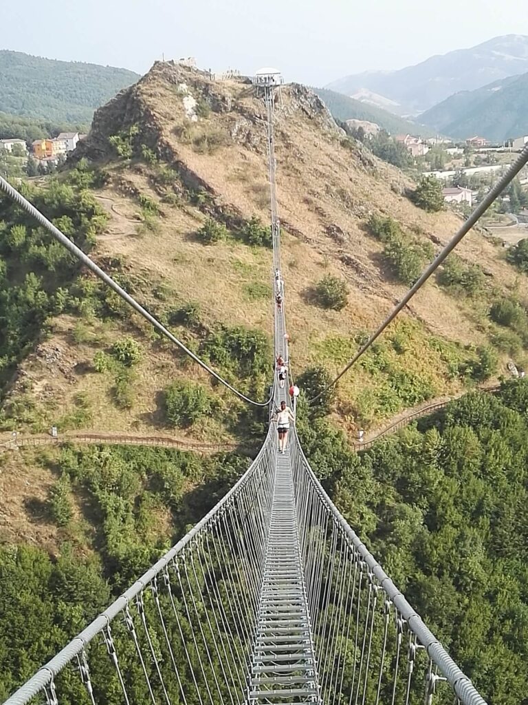 Attraversamento di un ponte tibetano sospeso, un'attività immersiva ideale per percorsi di team-building aziendale con impatto positivo sul territorio