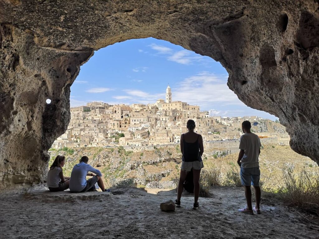 Affascinante vista sui Sassi di Matera incorniciata da una grotta, punto di partenza ideale per itinerari di turismo autentico e dialogo interculturale.